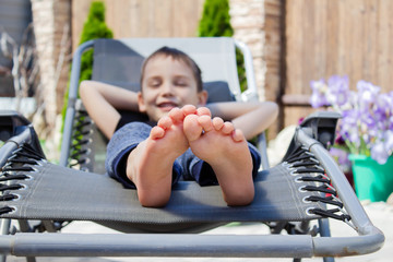 the boy's bare feet on the chaise longue. resting boy in the sun. The concept of relaxation. © Ekaterina