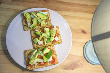 healthy toast with tomato avocado and cheese on wooden table
