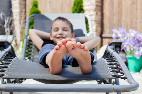 the boy's bare feet on the chaise longue. resting boy in the sun. The concept of relaxation.