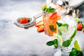 Fresh Mojito cocktail set with lime, mint, strawberry and ice in glass on gray background. Summer...