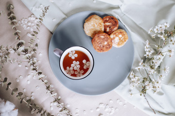 Breakfast in the morning, toasted beautiful cheesecakes on a plate on the tablecloth next to a spring bouquet of flowers