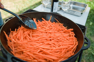 Pilaf Cooking in cauldron on fire outdoors series. Pieces of lamb meat, onion and carrot are fried...