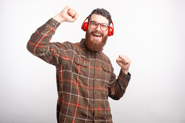 Fototapeta premium Happy bearded man wearing headphones is dancing over white background.