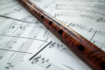 Vintage brown flute with patterns, on white notes with notes. Still life. Treble clefs. Learning to play the instrument.
