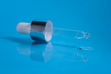 A pipette from serum bottle on the blue background.