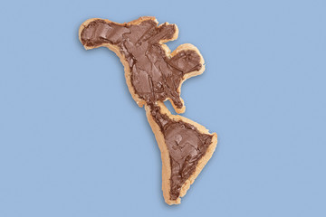 Toast bread in the form of the american continent with chocolate spread on a blue background