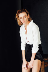 Portrait of a beautiful fashionable blonde woman in black shorts and white shirt