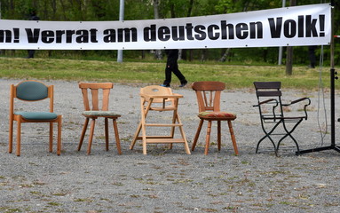 Protest-Transparent mit der Aufschrift: Lug, Betrug, Korruption! Verrat am deutschen Volk! Darunter fünf leere Stühle