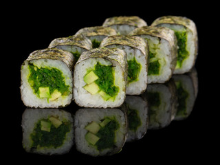 Vegetarian Sushi roll with chuka salad and avocado isolated on black background with reflection