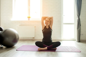 young girl in sportswear doing yoga at home on self-isolation, an athlete sits in a lotus position and meditates in a loft room interior