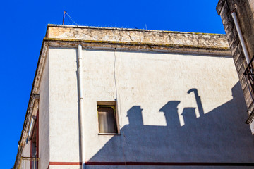 Shadows of four chimneys on an old building wall in Noicattaro, Metropolitan City of Bari, Apulia Region, Italy on a sunny September day