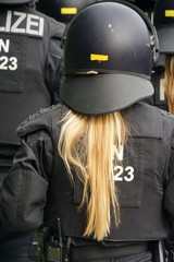 Polizistin mit langem blondem Zopf in schwarzer Uniform  und schwarzem Helm