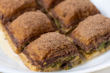 Turkish close up baklava with cocoa and milk on white plate