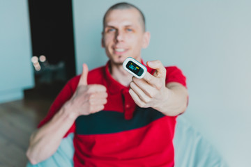 Mans shows hand with a pulse oximeter placed on the finger and thumbs up. Positive patient. Good...