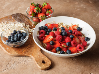 Healthy and diet traditional homemade breakfast - oatmeal flakes with fresh fruits strawberries and blueberries. Healthy lifestyle food homemade recipe.