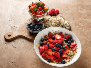 Oatmeal flakes with strawberries and organic berries in white plate with copy space background. Healthy lifestyle concept food.