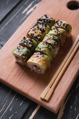 Sushi with salmon on a wooden board on a dark wooden background