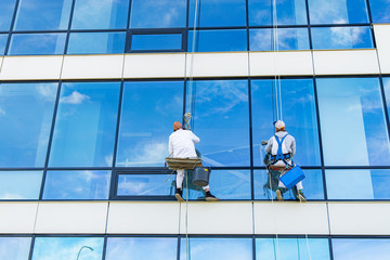 window cleaner two person back to camera dangerous work at height outside of building glass...