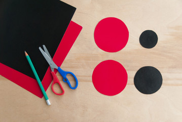 How to make cardboard colourful ladybug DIY. Homemade craft with ladybug tutorial. Glue, paper, scissors and pencil on a wooden table. Children's art project. Step by step tutorial. Step one