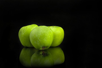 Green apples with reflection on a black background. Selective focus