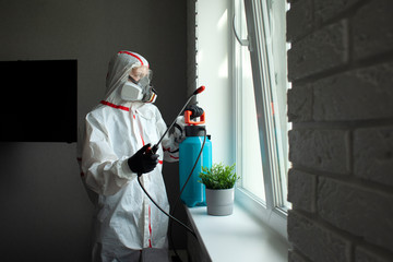 disinfection of the room from coronavirus. a man in a protective suit cleans the apartment of infections with a chemical agent