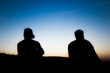 Fototapeta na wymiar silhouette of two people in front of the clear blue sky before sunrise