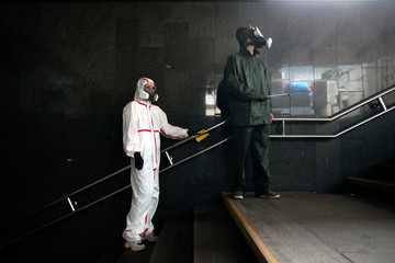 people in protective suits Hazmat disinfect handrails from viruses and infections, disinfection of public places