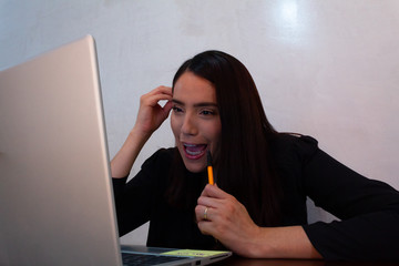 Young Hispanic woman in black clothes doing home office with a white laptop, bored and stressed...