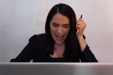 Young Hispanic woman in black clothes doing home office with a white laptop, bored and stressed...