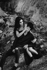 Asian couple in love hugs sitting on the rocks. Black-white
