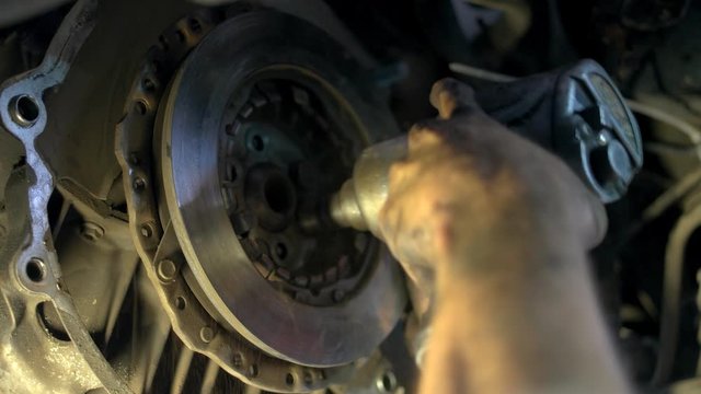 Close up machanic unscrewing bolts of a car clutch. Repairman uninstalling metal car clutch.
