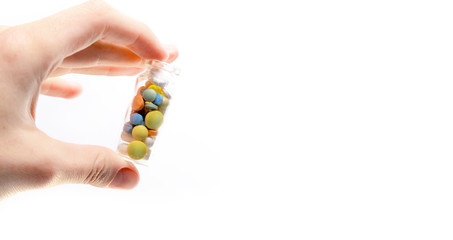 Hand holds a glass jar of pills and capsules. On white background. Copy space for text