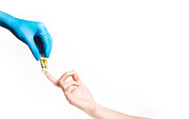 A doctor’s hand in a glove passes a glass jar with capsules and pills to the patient’s hand. On white background. Copy space for text