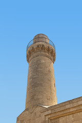 Minaret in the Palace of Shirvanshahs against the blue sky, in the historical district of Baku