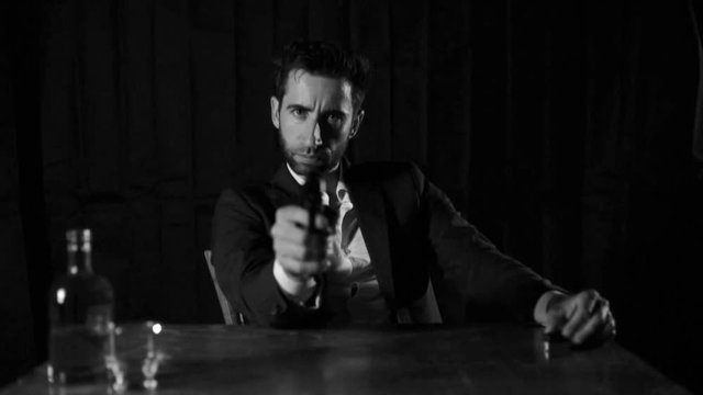 Man with the gun, detective sitting on the desk.