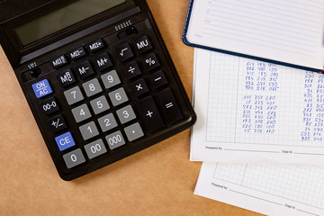 Flat lay of calculator with dairy and documents on the table.