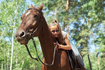 Girl child riding horse, summer horse ride in the forest, girl lovingly hugged horse