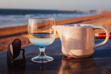 Glass of wine and tea on a bar at sunset.