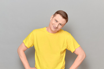 Obraz premium Portrait of happy friendly blond mature man holding hands on hips