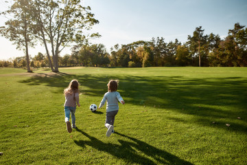 Children are our most valuable natural resource. Two kids playing with a ball on meadow