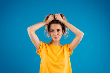 Smiling happy teenager girl portrait on blue wall background. Beauty teen style with hair tails