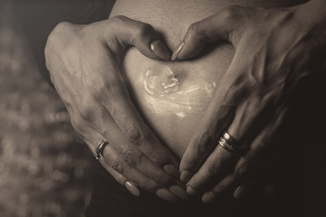 Babybauch mit Händen in Herzform und Ultraschall Bild 