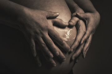 Babybauch mit Händen in Herzform und Ultraschall Bild 