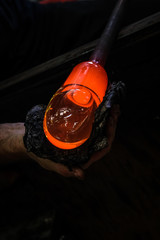 Artist glass blower working glass paste on his workbench. A glass crafter is burning and blowing an...