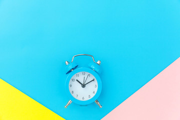 Ringing twin bell classic alarm clock isolated on blue yellow pink pastel colorful geometric...