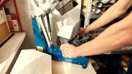 Making ideas come to life. Cropped shot of hands of man using machine for printing on baseball cap...