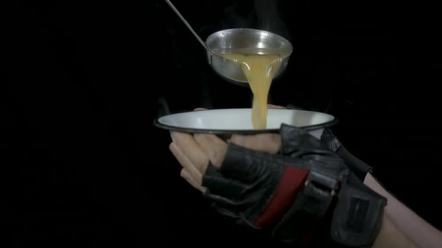 Food for the needy. A homeless man is poured into a bowl of hot soup. Homeless food concept.