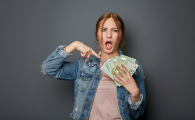 Portrait of a natural and authentic beautiful young woman, teenager with many 100 Euro banknotes in...