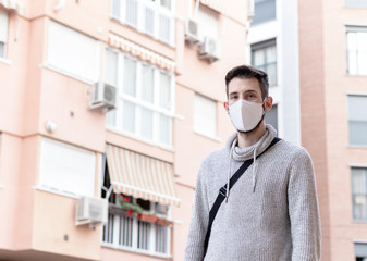 Fototapeta na wymiar Young man with facial mask taking a walk in the city. New normal life style