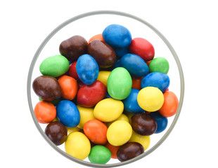 Multicolored chocolate coated candies in a glass on a white background